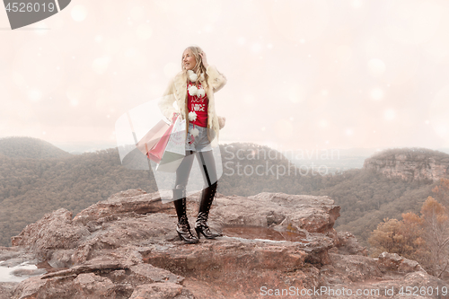 Image of Female holding shopping bags a wintry scene Christmas in the mountains