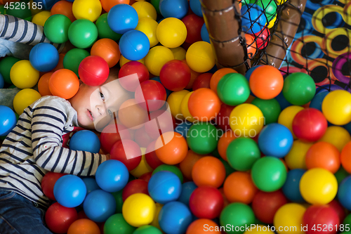 Image of boy having fun in pool with colorful balls