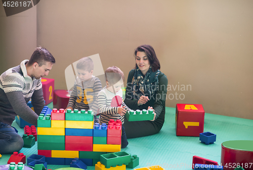 Image of young parents and kids having fun at childrens playroom