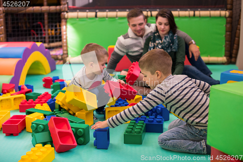 Image of young parents and kids having fun at childrens playroom