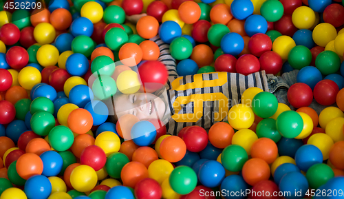 Image of boy having fun in pool with colorful balls