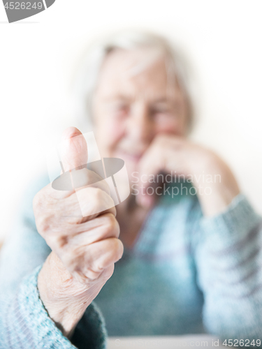 Image of Happy 96 years old elderly woman giving a thumb up and looking at camera.