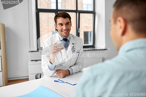 Image of doctor showing medicine to patient at hospital