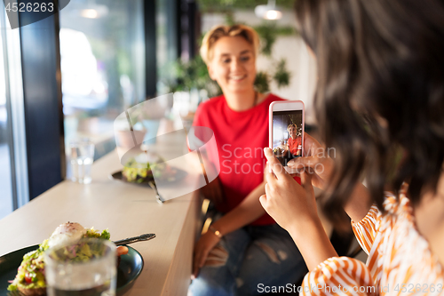 Image of women having lunch and photographing at cafe