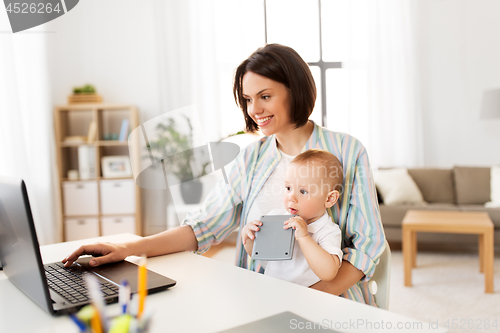 Image of working mother with baby boy and laptop at home