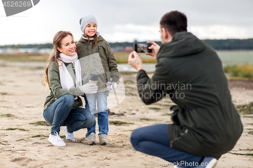 Image of family photographing by smartphone on autumn beach