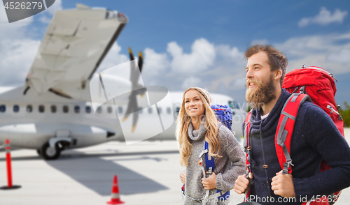 Image of couple of tourists with backpacks over plane