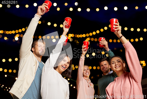 Image of friends toasting party cups on rooftop at night