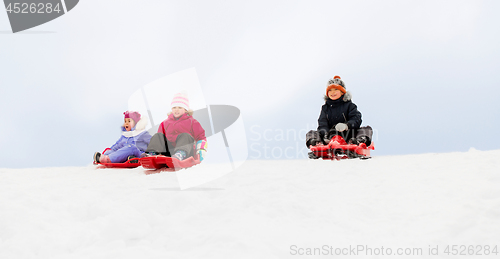 Image of kids sliding on sleds down snow hill in winter