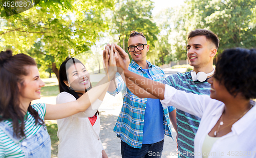 Image of happy friends making high five in park