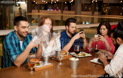 Image of friends with smartphones at restaurant