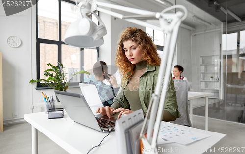 Image of creative woman with laptop working at office