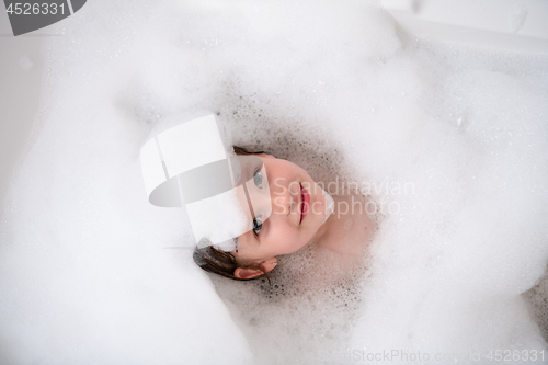 Image of top view of little girl in bath playing with foam