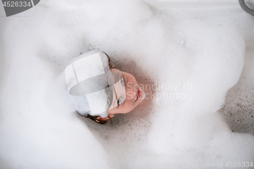 Image of top view of little girl in bath playing with foam