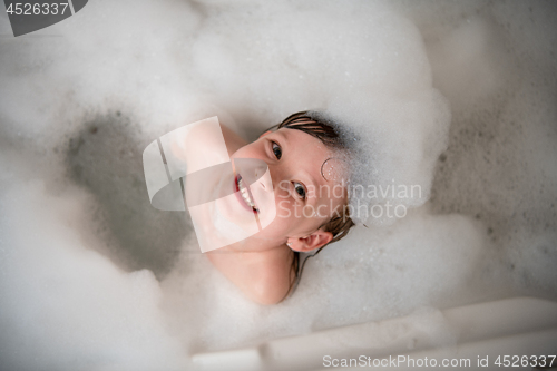 Image of top view of little girl in bath playing with foam