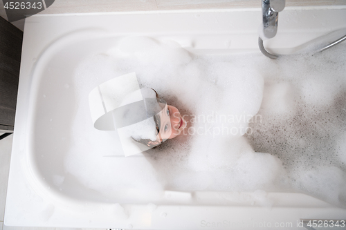 Image of top view of little girl in bath playing with foam