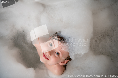 Image of top view of little girl in bath playing with foam