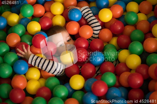 Image of boy having fun in hundreds of colorful plastic balls