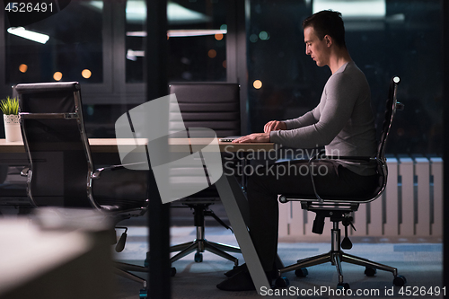 Image of man working on laptop in dark office