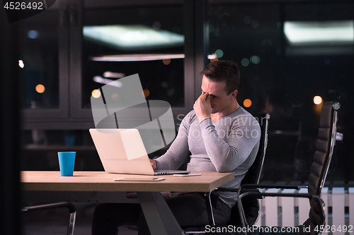 Image of man working on laptop in dark office