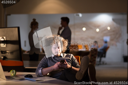 Image of businessman sitting with legs on desk at office