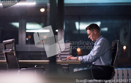 Image of man working on laptop in dark office