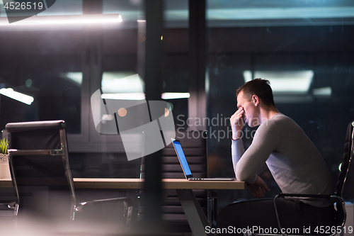 Image of man working on laptop in dark office