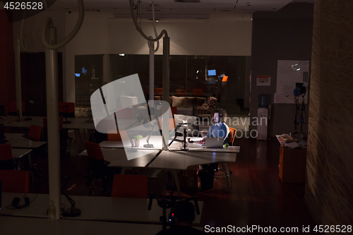 Image of man working on computer in dark office