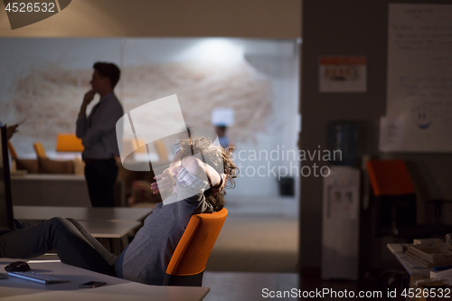 Image of businessman sitting with legs on desk at office