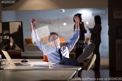 Image of businessman sitting with legs on desk at office