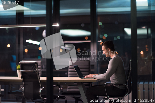 Image of man working on laptop in dark office