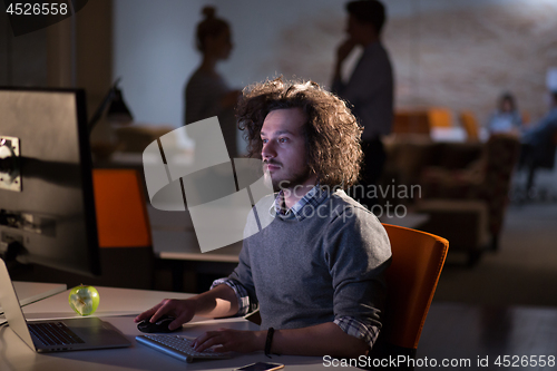 Image of man working on computer in dark office