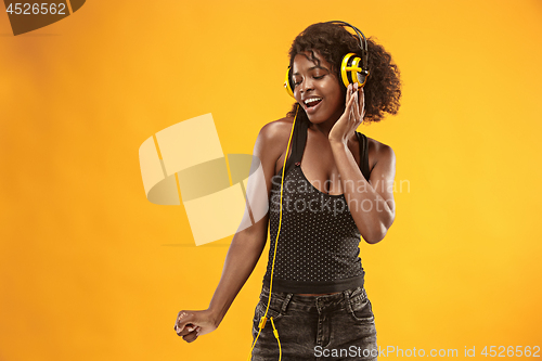 Image of Studio portrait of adorable curly girl happy smiling during photoshoot. Stunning african woman with light-brown skin relaxing in headphones