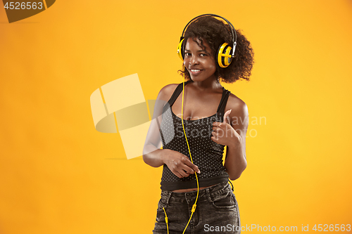 Image of Studio portrait of adorable curly girl happy smiling during photoshoot. Stunning african woman with light-brown skin relaxing in headphones