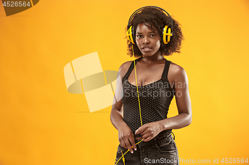 Image of Studio portrait of adorable curly girl happy smiling during photoshoot. Stunning african woman with light-brown skin relaxing in headphones