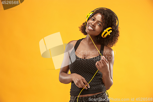 Image of Studio portrait of adorable curly girl happy smiling during photoshoot. Stunning african woman with light-brown skin relaxing in headphones