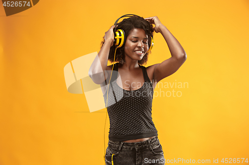 Image of Studio portrait of adorable curly girl happy smiling during photoshoot. Stunning african woman with light-brown skin relaxing in headphones