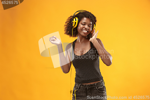 Image of Studio portrait of adorable curly girl happy smiling during photoshoot. Stunning african woman with light-brown skin relaxing in headphones