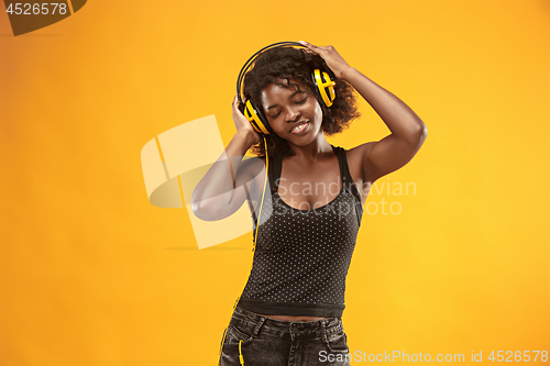 Image of Studio portrait of adorable curly girl happy smiling during photoshoot. Stunning african woman with light-brown skin relaxing in headphones