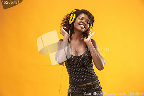 Image of Studio portrait of adorable curly girl happy smiling during photoshoot. Stunning african woman with light-brown skin relaxing in headphones
