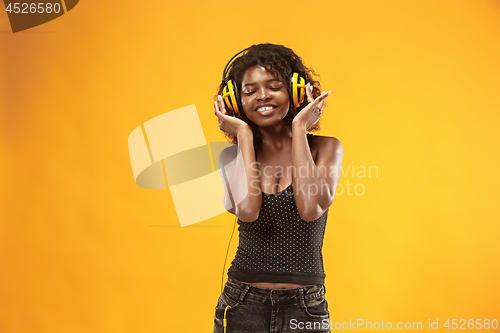 Image of Studio portrait of adorable curly girl happy smiling during photoshoot. Stunning african woman with light-brown skin relaxing in headphones