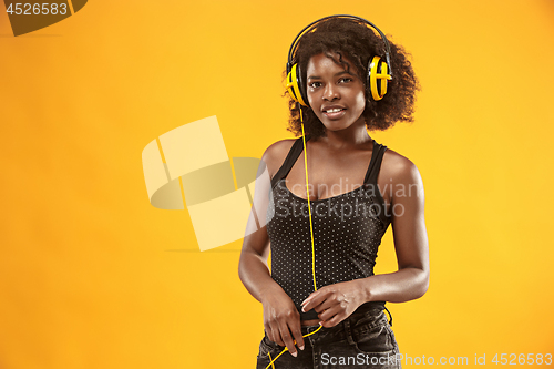 Image of Studio portrait of adorable curly girl happy smiling during photoshoot. Stunning african woman with light-brown skin relaxing in headphones