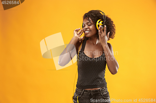 Image of Studio portrait of adorable curly girl happy smiling during photoshoot. Stunning african woman with light-brown skin relaxing in headphones