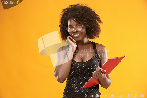 Image of portrait of a beautiful friendly African American woman with a curly afro hairstyle and red folder