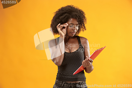 Image of portrait of a beautiful friendly African American woman with a curly afro hairstyle and red folder