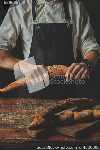 Image of Male hands break the baguette