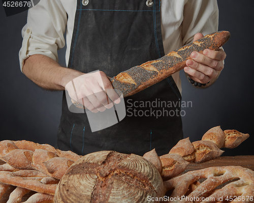 Image of Men\'s hands hold a baguette