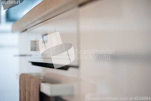 Image of Modern kitchen surface of new electrical stove with clock indicator and textile towel on it. Photo with shallow depth of field.