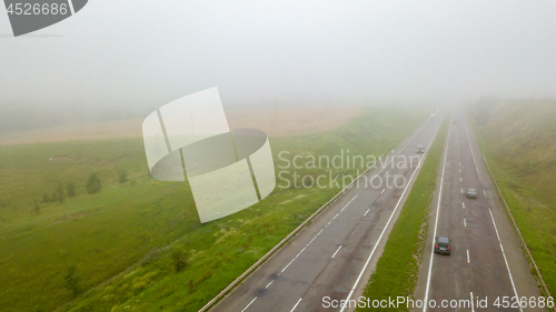 Image of Aerial view panoramic view of the foggy road with cars around the field. Photo from the drone