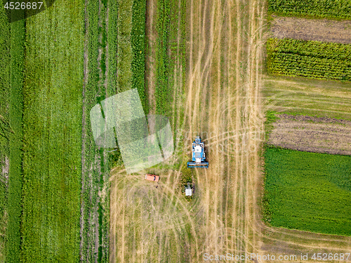 Image of Agricultural field after harvesting and combine harvester reaps a crop, red car on a field. Aerial view from the drone. Top view